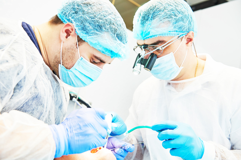 two male dentists replacing a patient's missing teeth two male dentists replacing a patient's missing teeth